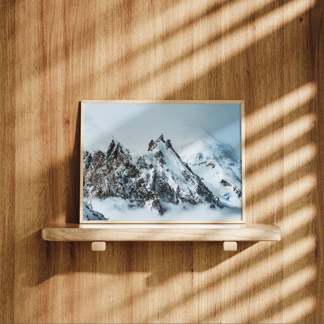 Framed Aiguille du Midi print displayed on wooden shelf with light shadows