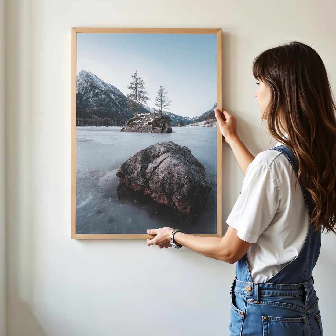 Woman hanging Hintersee winter landscape print on white wall
