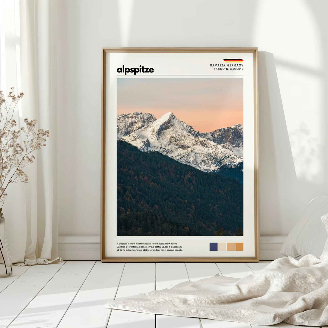 Natural wood framed Alpspitze Bavaria Germany print leaning against white wall on white floorboards in minimal Scandinavian interior
