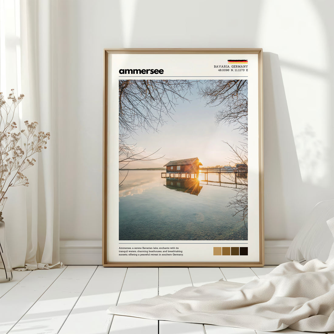 Natural wood framed Ammersee Bavaria Germany boathouse print leaning against white wall on white floorboards in minimal Scandinavian interior