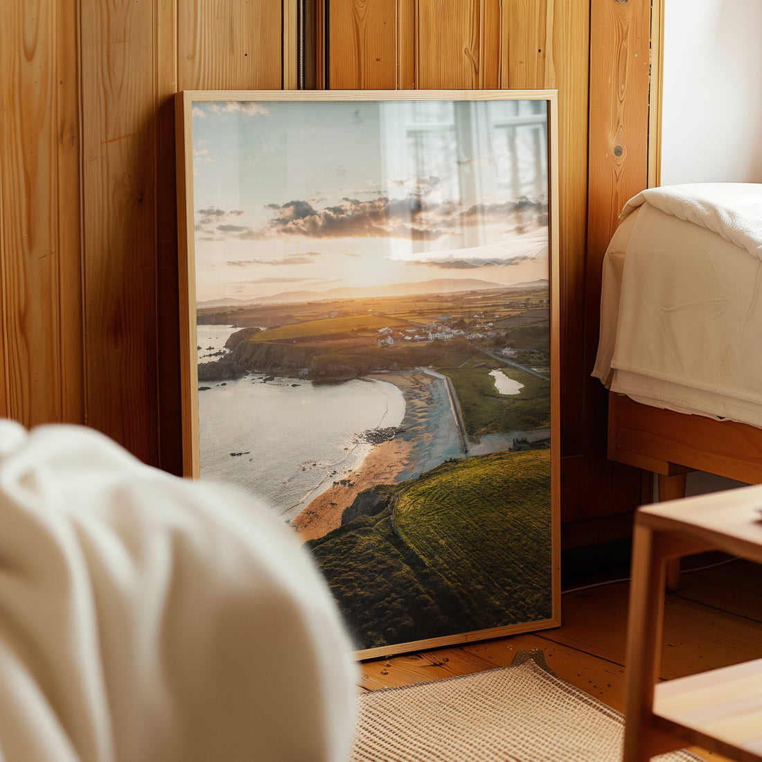 Framed photo of Annestown Beach propped beside a bed with wooden wall panels