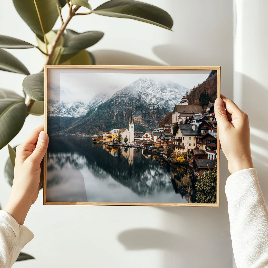 Framed Hallstatt photo print being held in hands with leafy background.