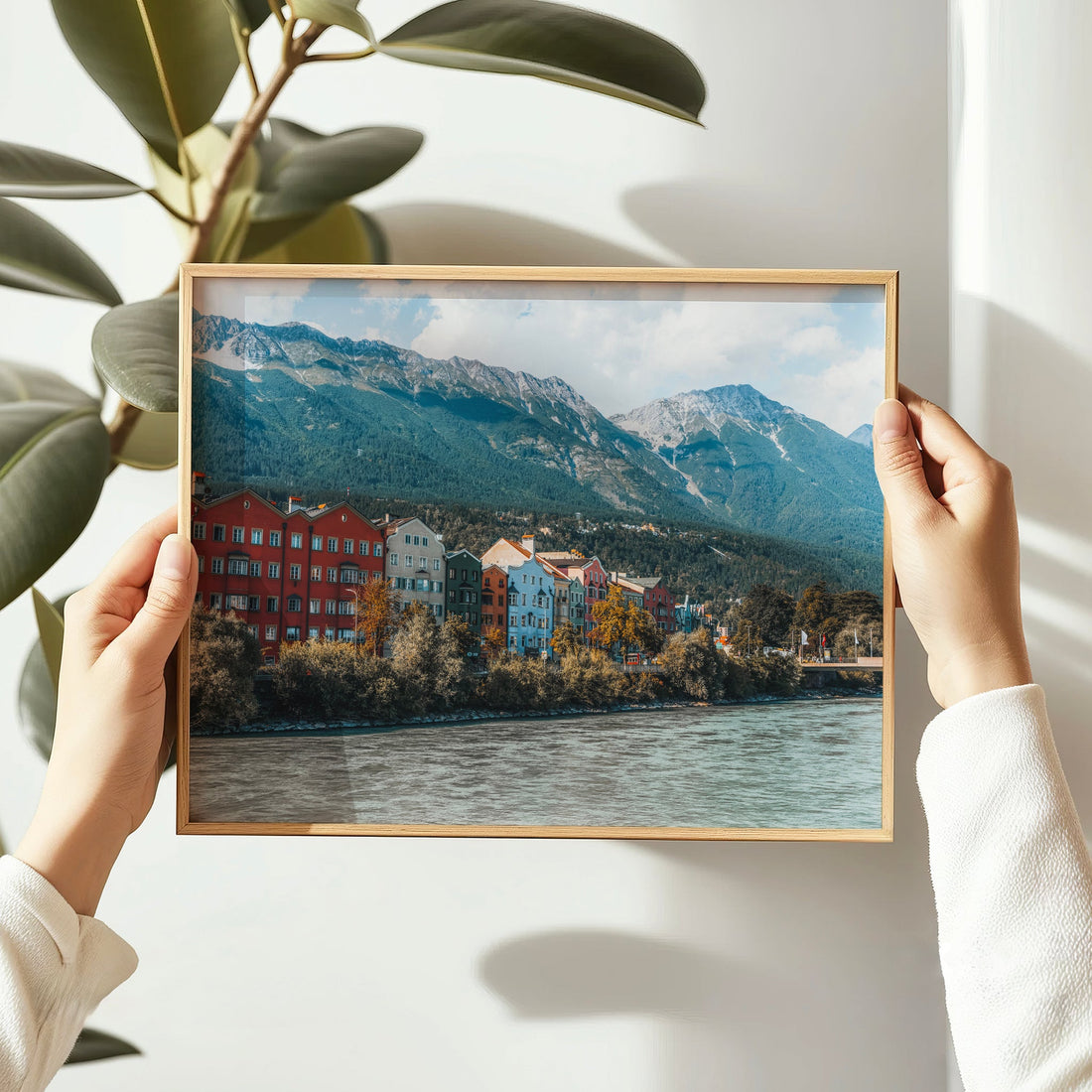 Woman hanging framed Innsbruck Austria wall art print in bright interior.