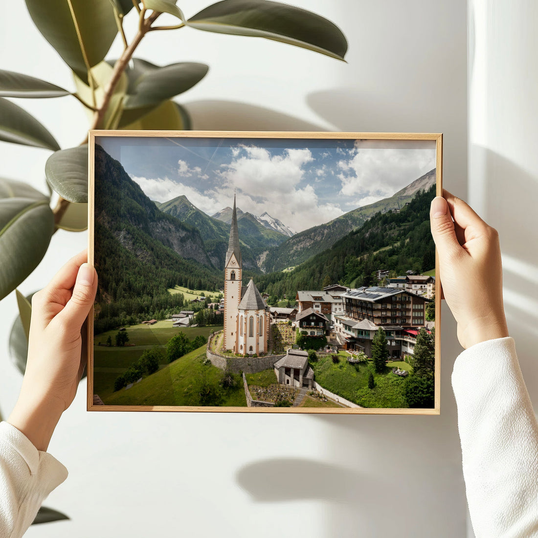 Hands holding Heiligenblut wall art featuring the church and mountains