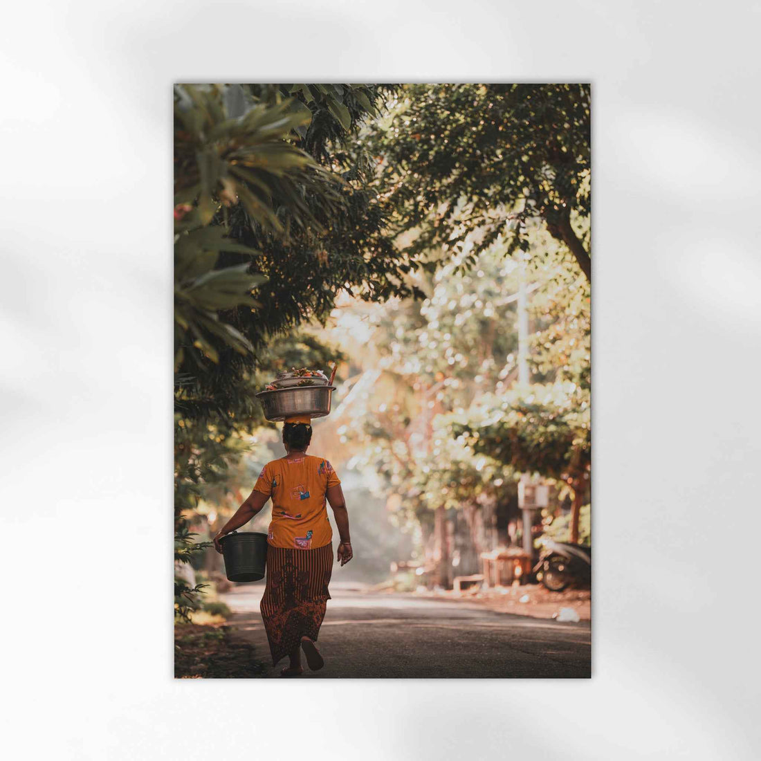 Balinese woman carrying offerings on head through golden jungle village road Bali photography print unframed on white background