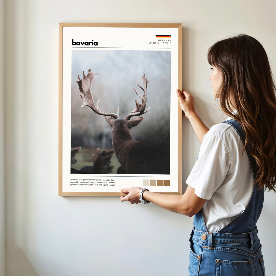 Woman hanging framed Bavaria red deer stag Germany wildlife photography print in natural oak frame on white wall