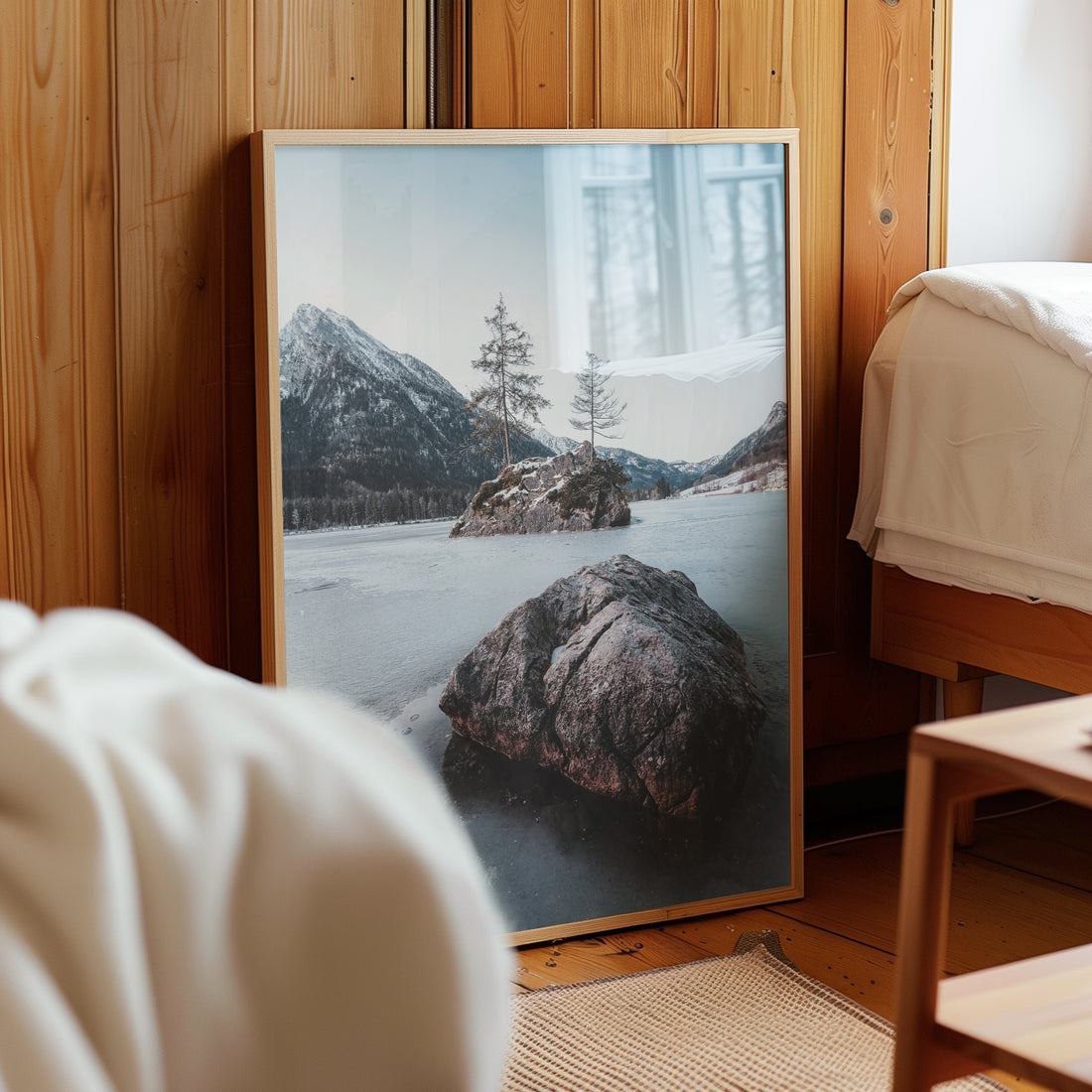 Framed Hintersee winter scene resting by a wooden bed in a cosy room