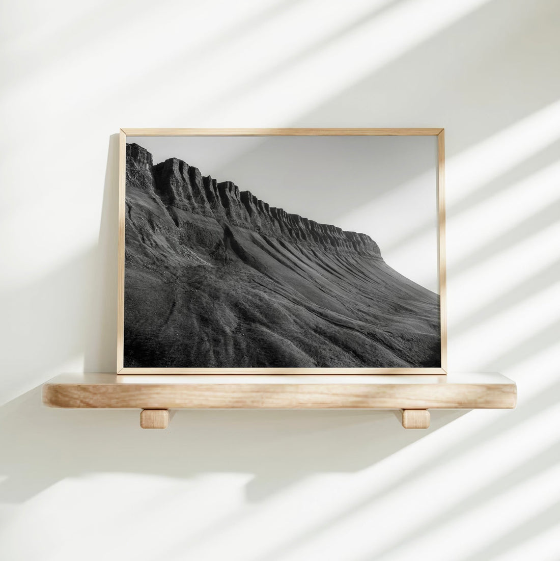 Framed Benbulbin landscape print placed on white shelf with shadows