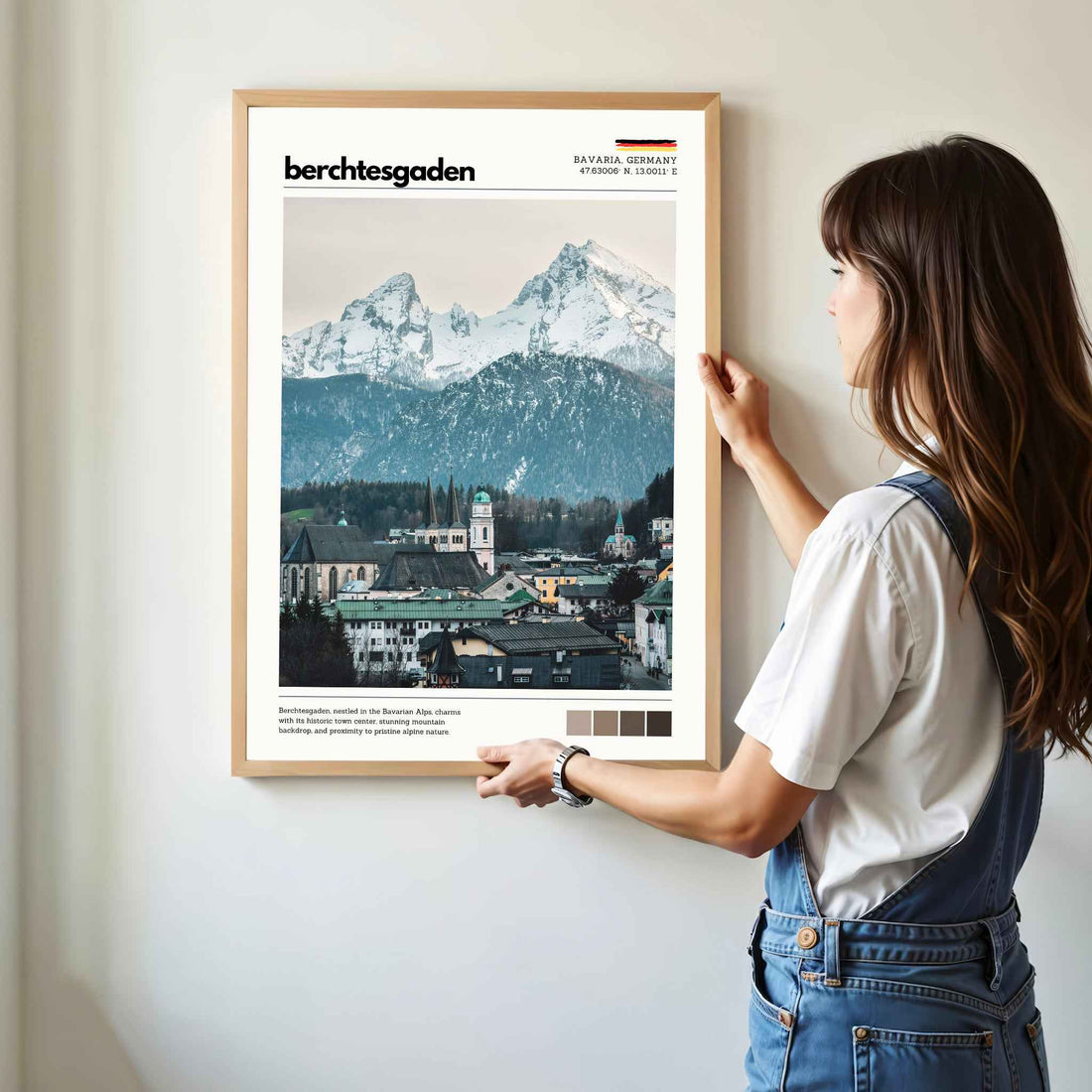 Woman hanging framed Berchtesgaden Bavaria Germany town and Watzmann photography print in natural oak frame on white wall