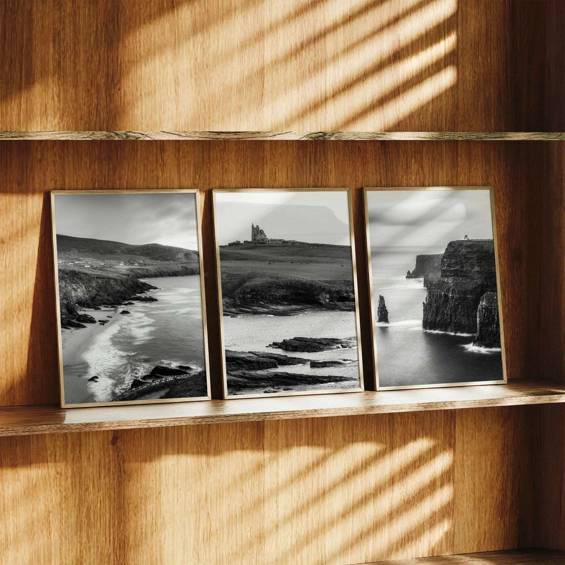 Black and white Irish coastal wall art set of three displayed on a wooden shelf with natural light
