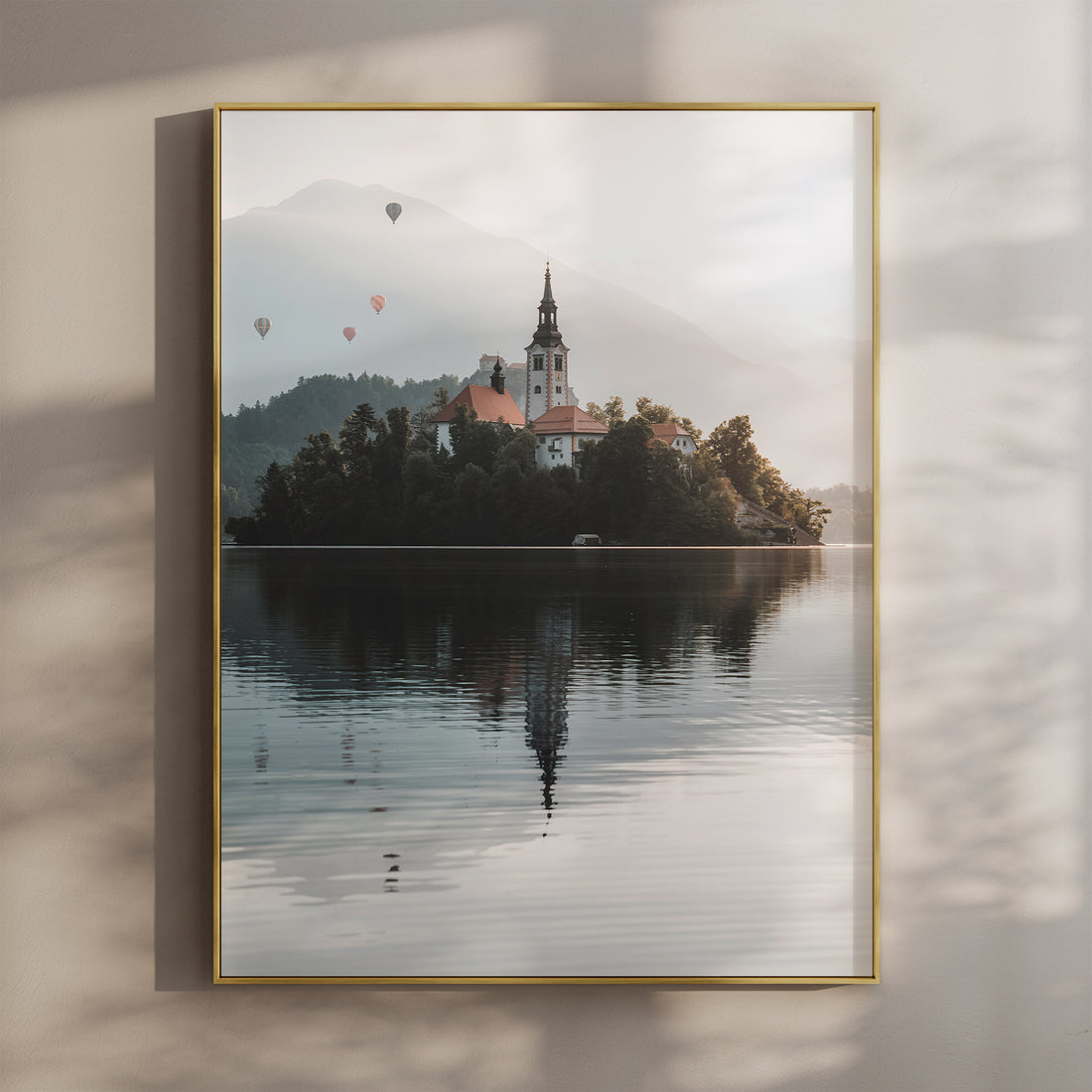 Lake Bled church at sunrise with soft reflection and layered mountains