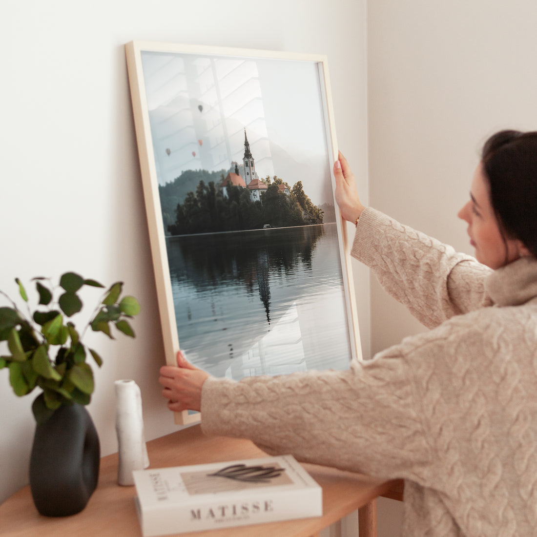 Framed Lake Bled wall art displayed on a shelf with modern minimal decor