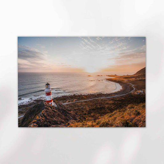 Unframed Cape Palliser lighthouse landscape fine art print on white background showing red and white striped lighthouse at golden hour over curved coastline