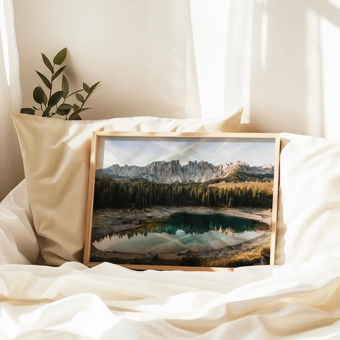 Framed Dolomites Lago di Carezza print resting on white bedding