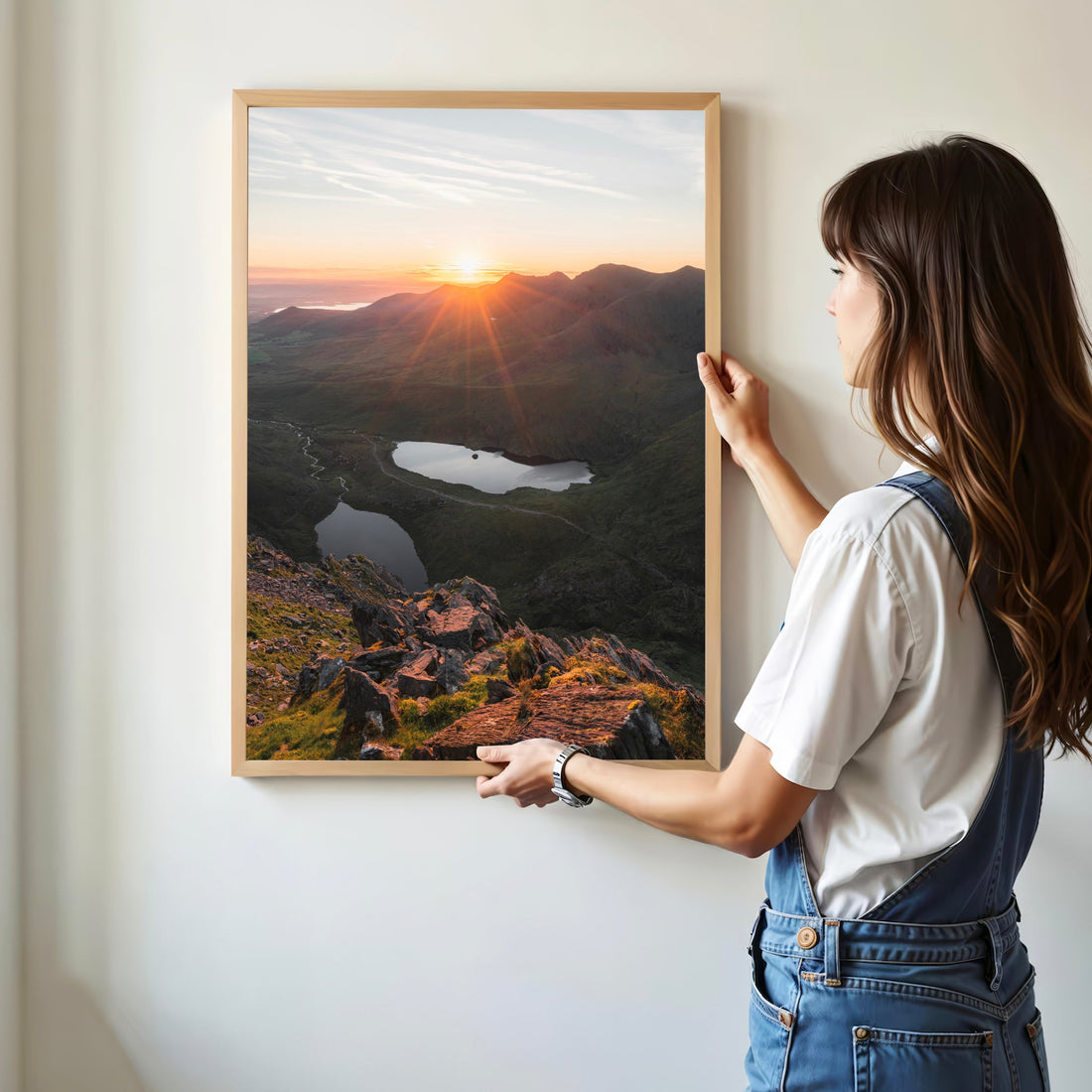 Woman hanging Carrauntoohil sunrise wall art in bright room