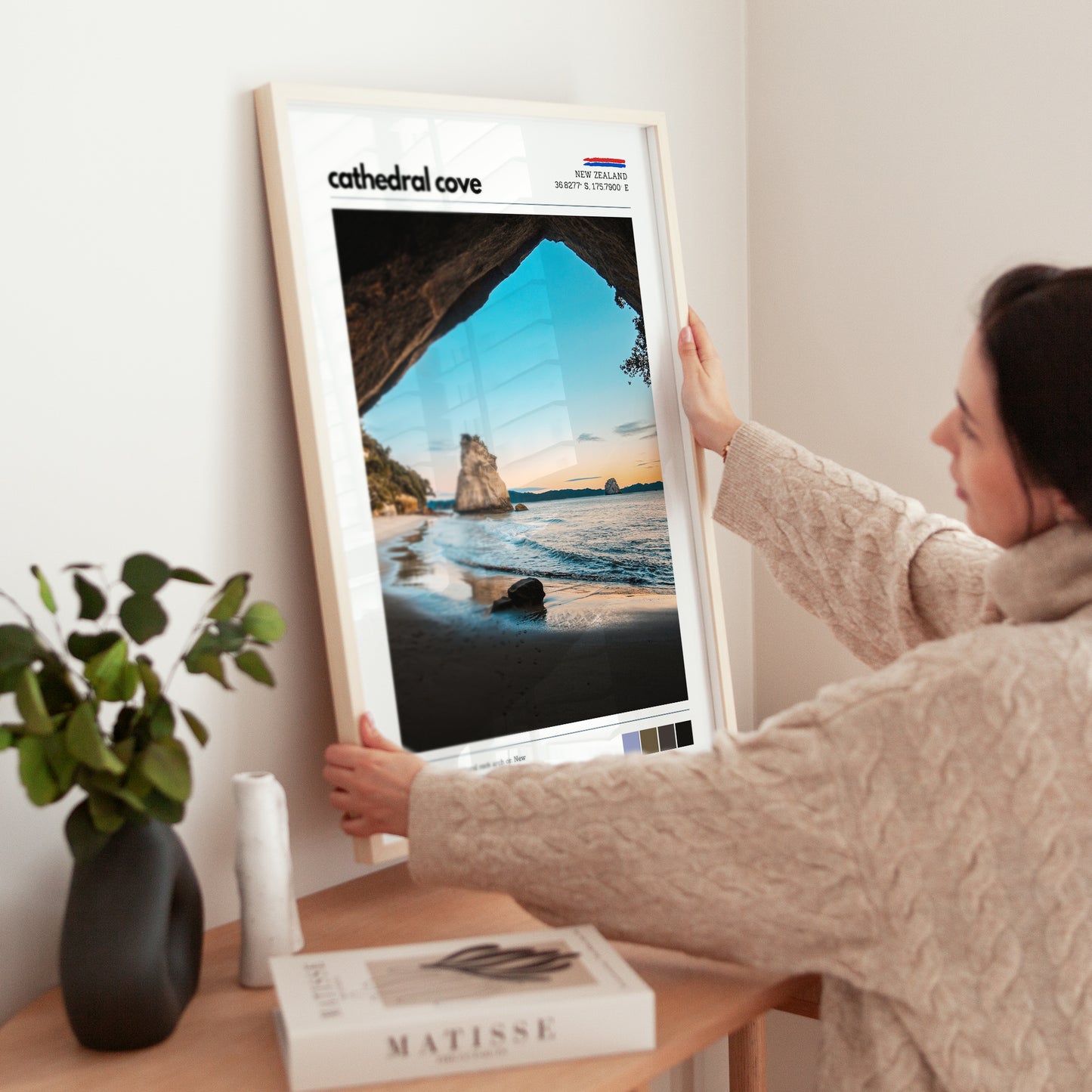 Close-up of hands adjusting a framed Cathedral Cove wall art print