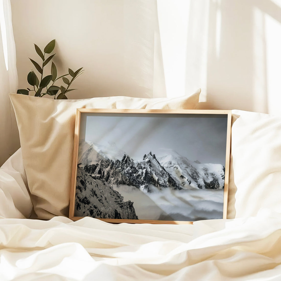 A framed fine art photograph of Aiguille du Midi resting on white bedding