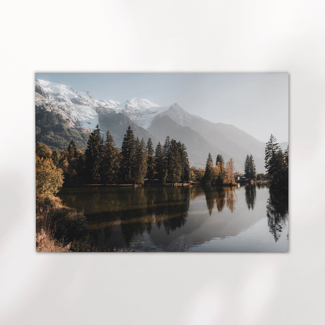 Tranquil Chamonix lake wall art showing alpine trees and Mont Blanc foothills mirrored in still water.