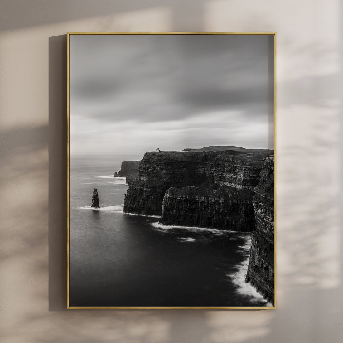 Framed black and white photo print of Cliffs of Moher on a wall with moody shadows