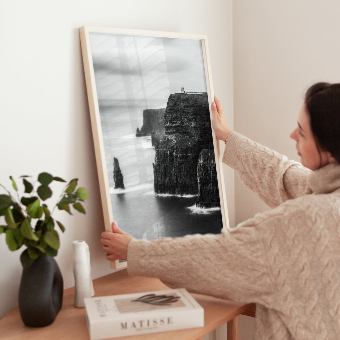 Woman styling black and white Cliffs of Moher print on wooden cabinet