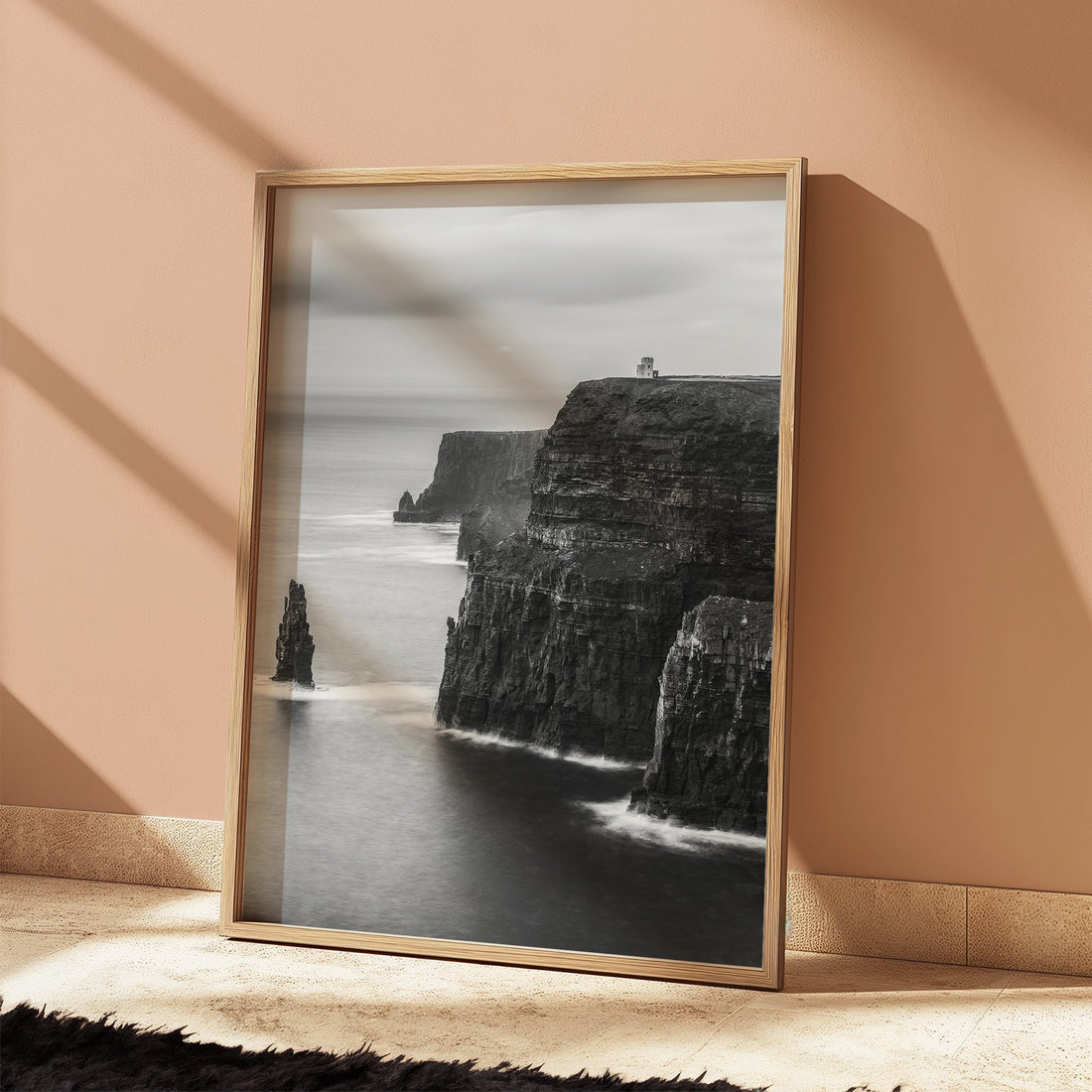 Black and white Cliffs of Moher wall art leaning against pink wall in sunlight