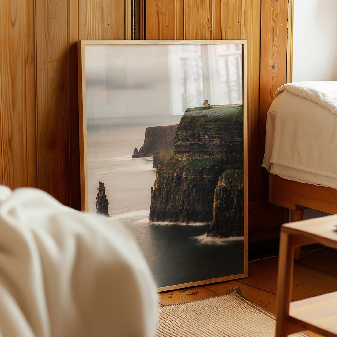 Framed Cliffs of Moher photography print leaning against a wood-panelled bedroom wall