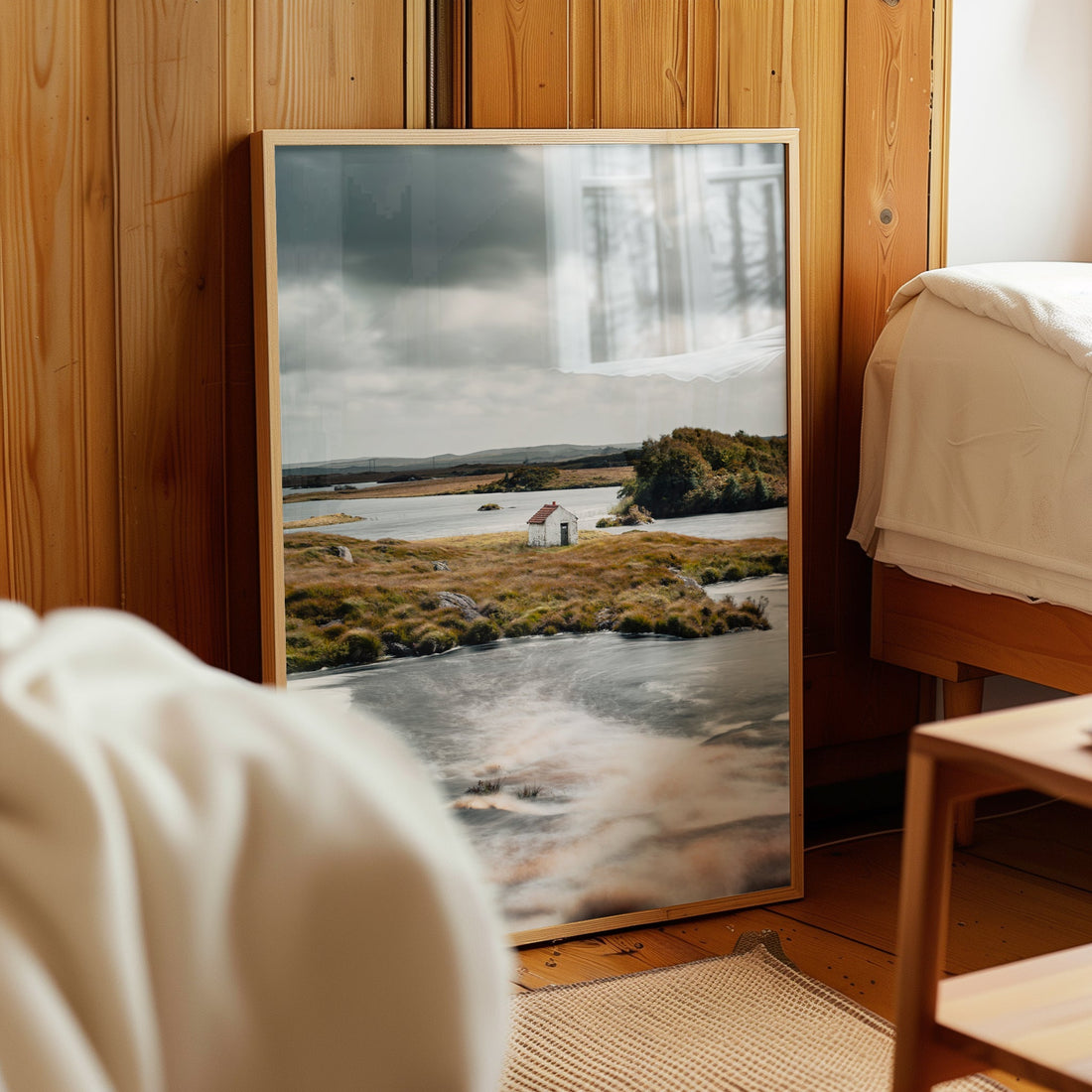 Rustic framed print of a lakeside hut in Connemara resting on a wooden bedroom wall