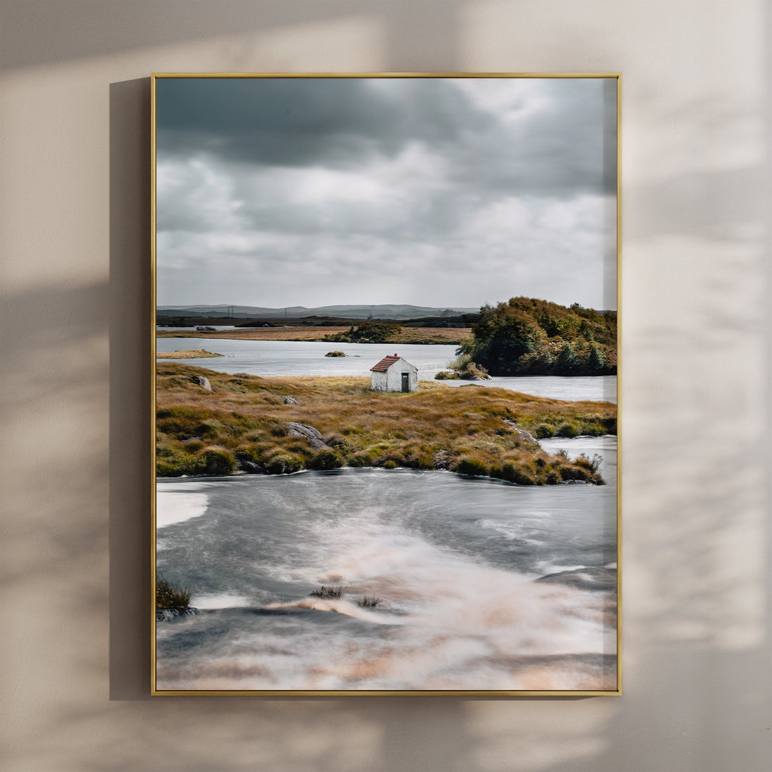 Fine art print of a small white hut on a lake in Connemara, Ireland with dramatic clouds