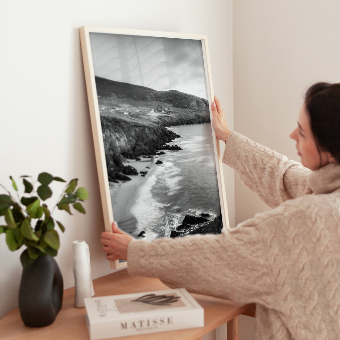 Woman positioning black and white Coumeenoole Beach print on wooden cabinet