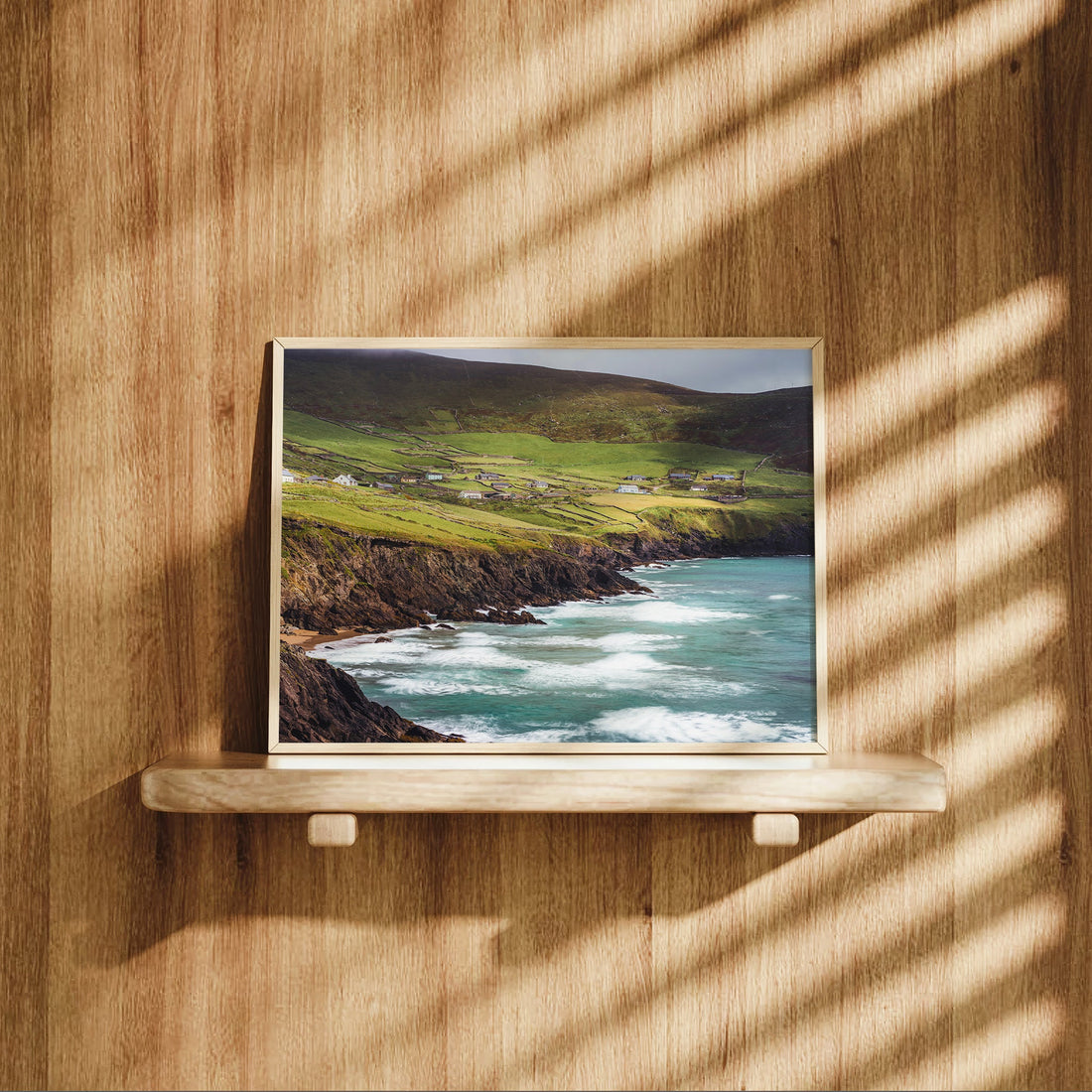 Coastal landscape print of Coumeenoole Beach styled on a wooden shelf with sunlit shadows