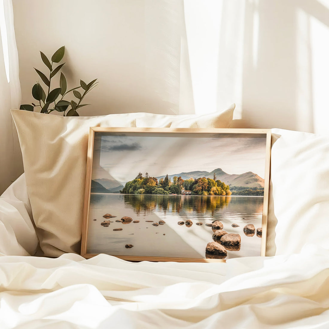 Framed Derwentwater photography print resting on bed in cozy interior