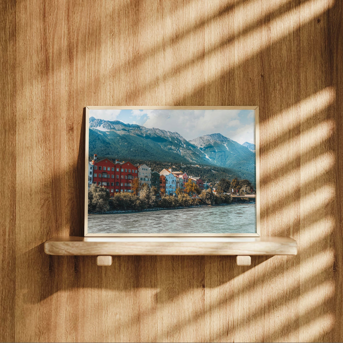 Innsbruck print leaning against wooden wall in cozy bedroom setting.