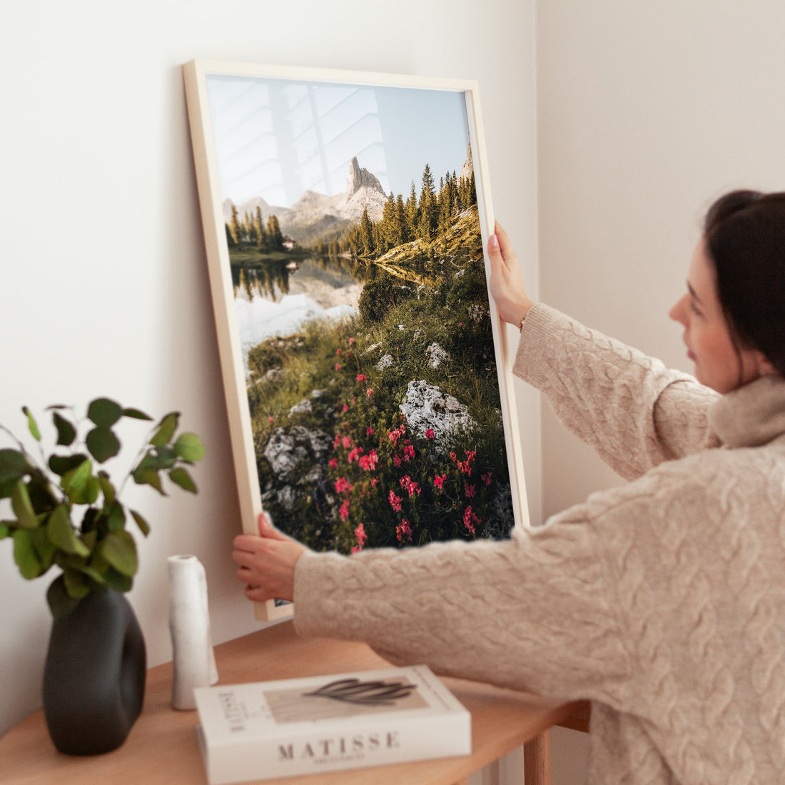 Woman hanging a framed print of Lago di Federa landscape in home interior