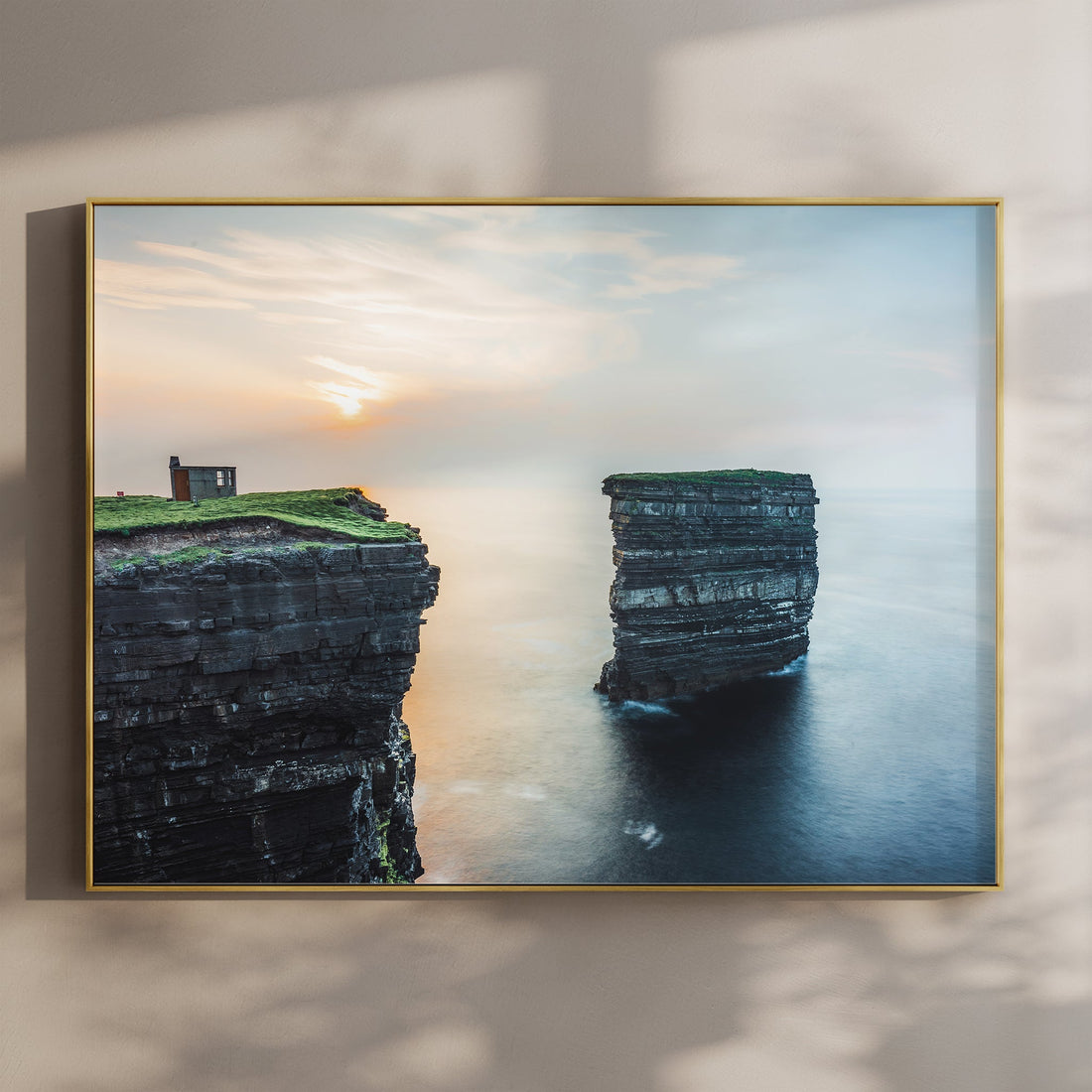 Framed print of Downpatrick Head sea stack at sunset with soft golden light on coastal cliffs