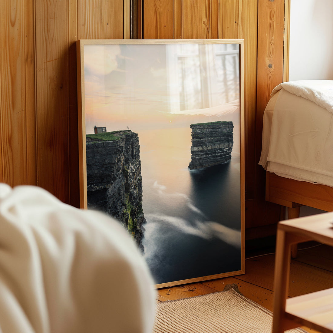 Downpatrick Head wall print leaning in cosy wooden bedroom with warm morning light.