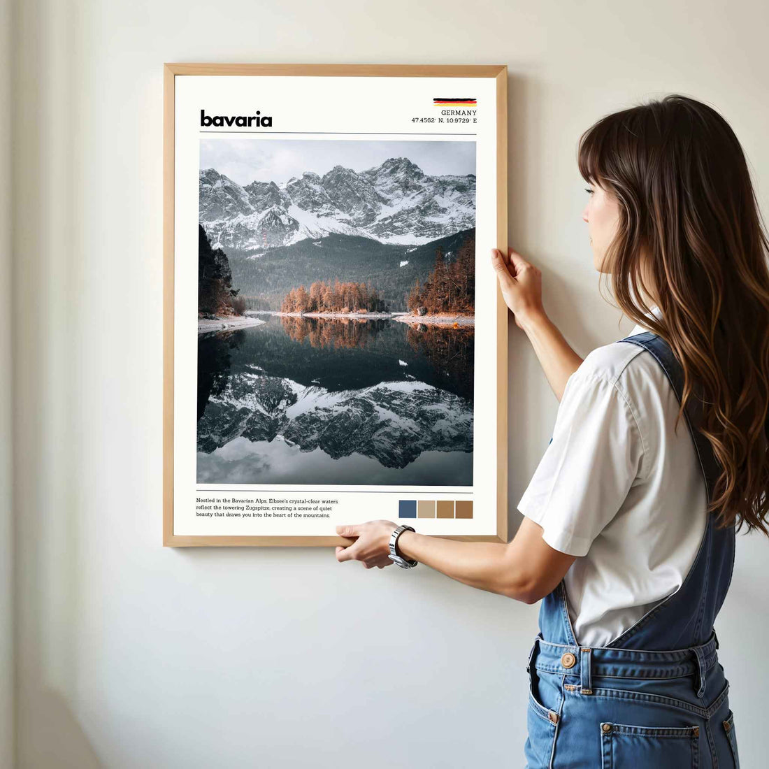 Woman hanging framed Eibsee Zugspitze Bavaria Germany photography print in natural oak frame on white wall