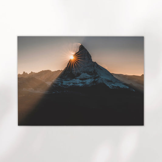 Minimalist print of the Matterhorn with a sun flare, on a clean white wall.