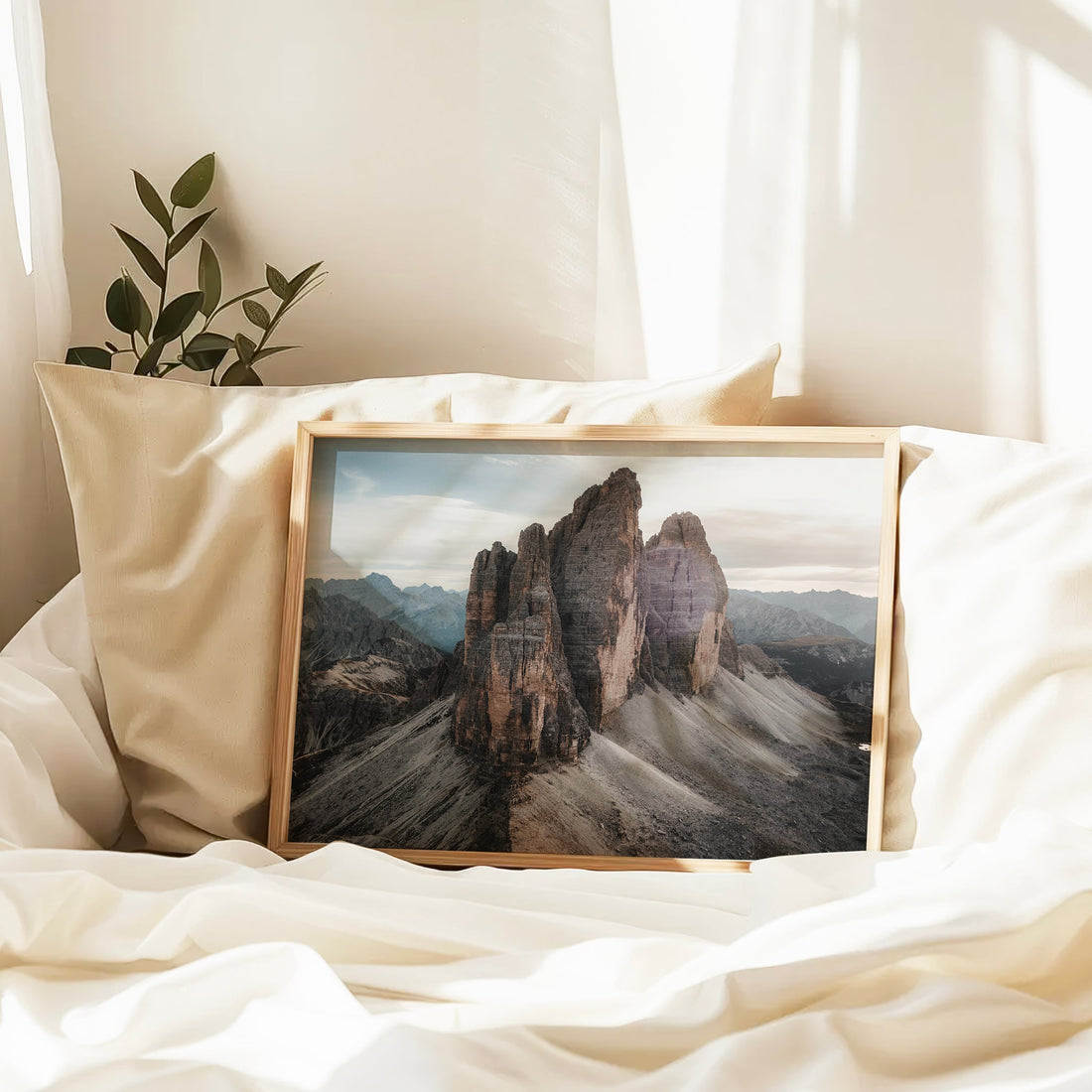 Tre Cime framed print resting on cream bedding in soft light, cosy interior decor