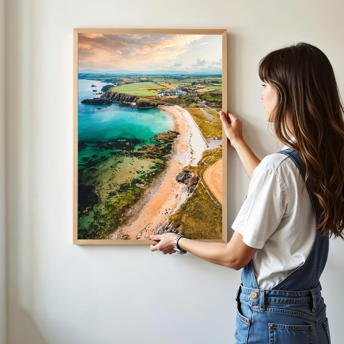 Woman holding framed Annestown Beach print against a white wall