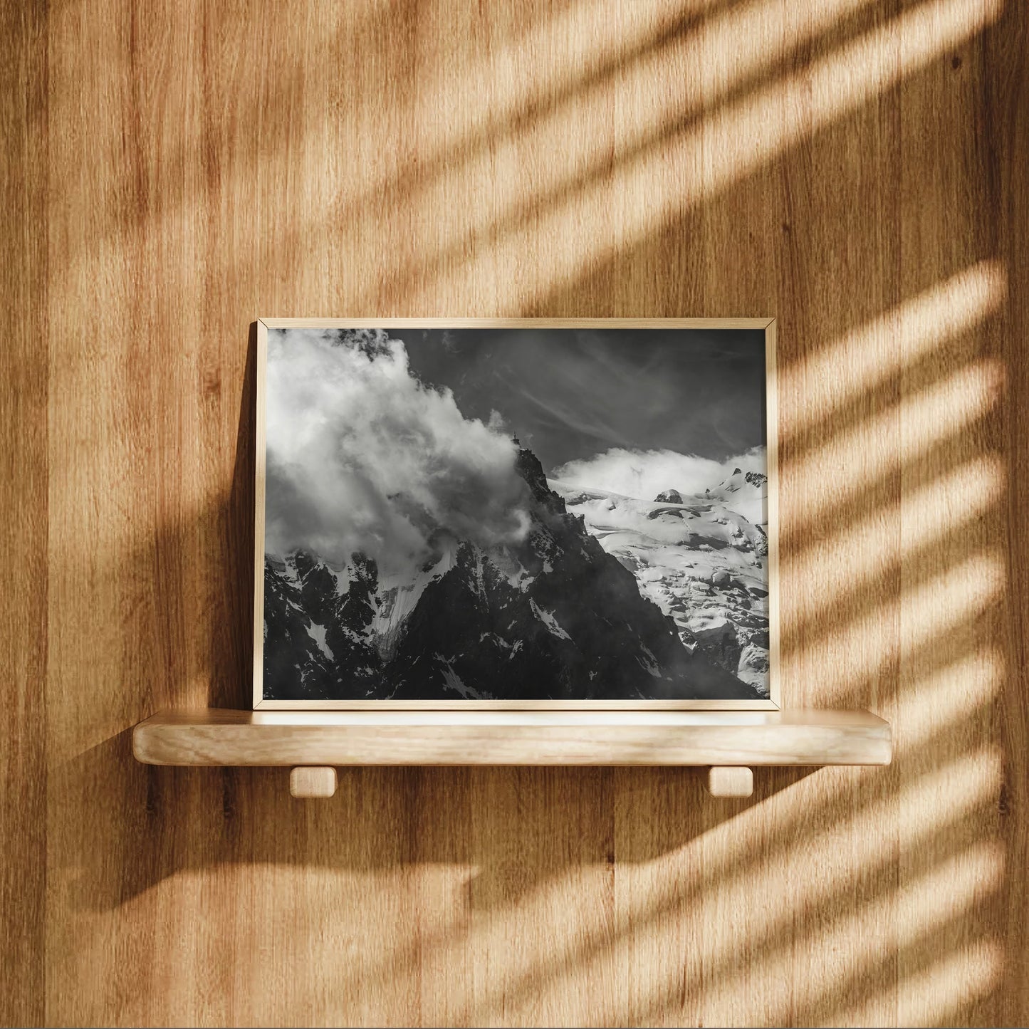 Monochrome landscape of the French Alps featuring Aiguille du Midi partially veiled in alpine clouds.