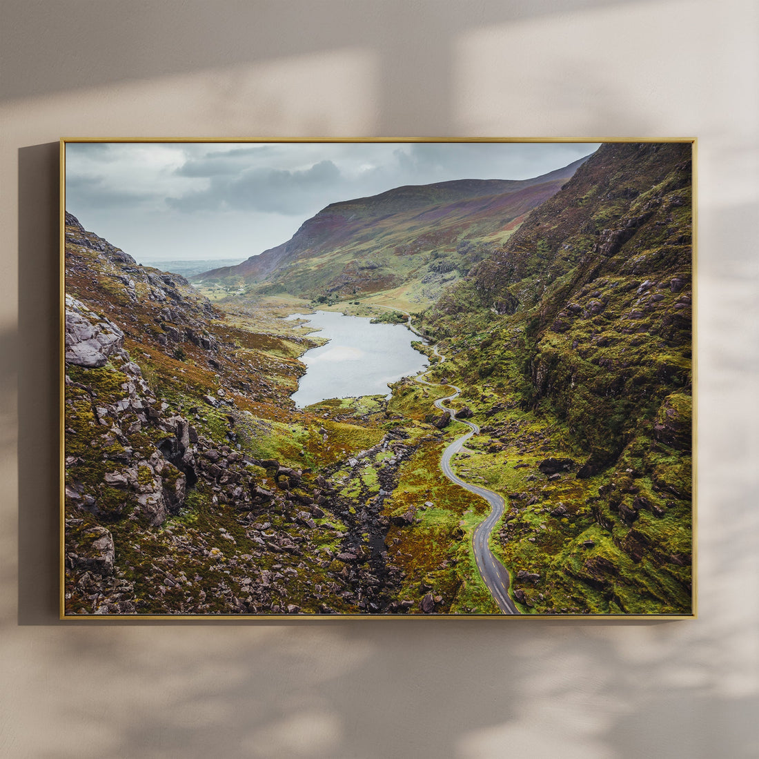 A framed aerial view of the Gap of Dunloe in Ireland with a winding road through lush green mountains.
