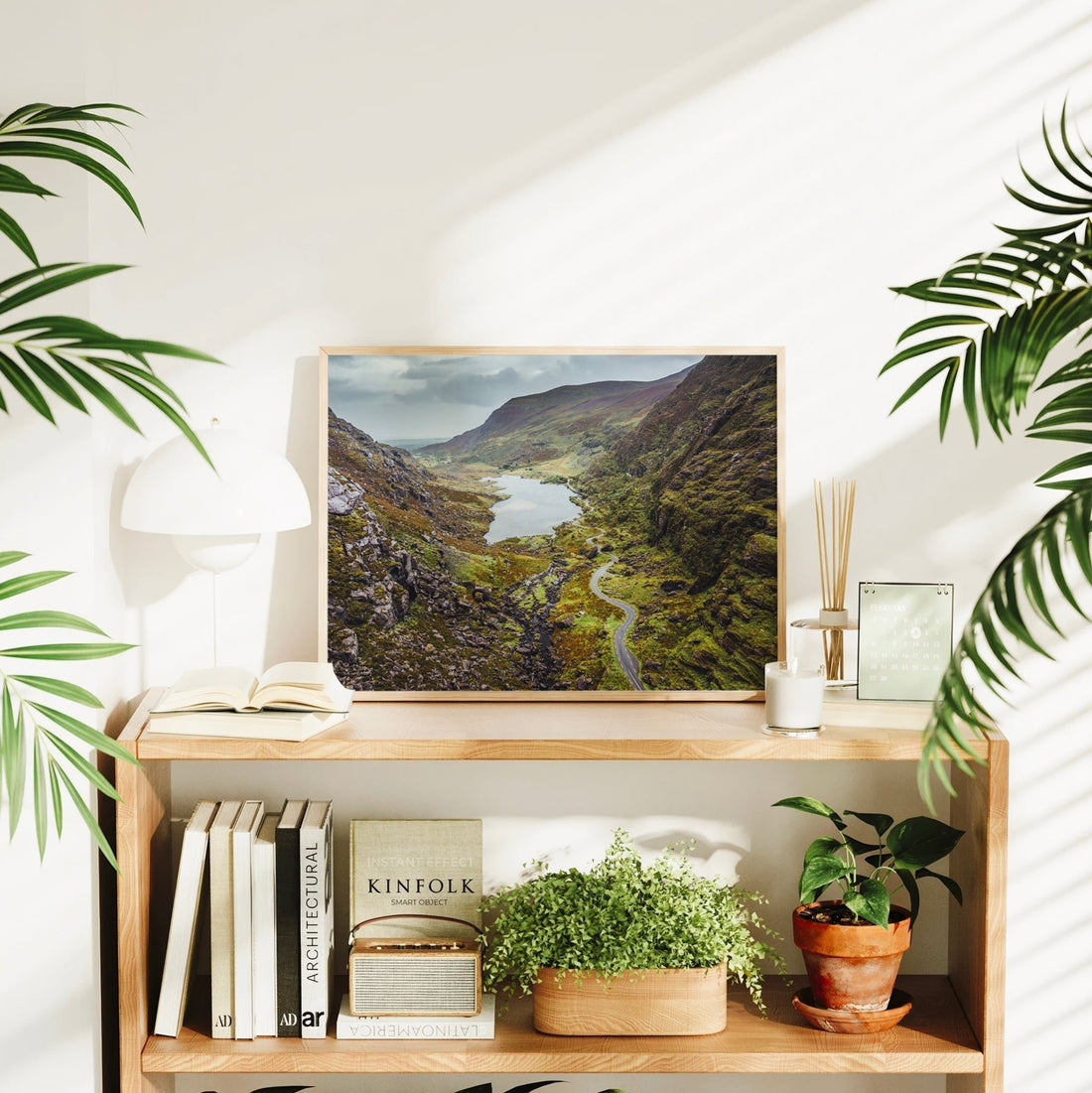 Framed Irish landscape wall art of the Gap of Dunloe displayed on a modern bookshelf with decor.