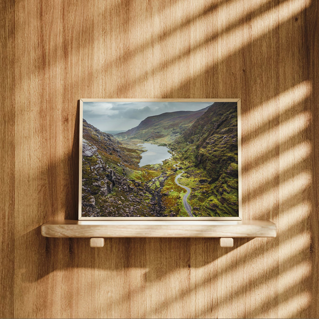 Gap of Dunloe landscape print on a wood shelf, capturing golden hour light through a mountain valley.