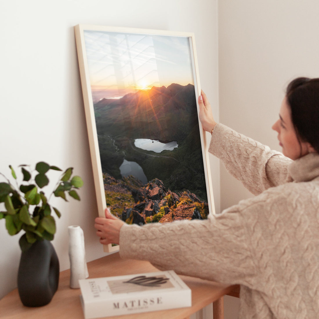 Woman positioning Carrauntoohil sunrise print on table with warm interior decor