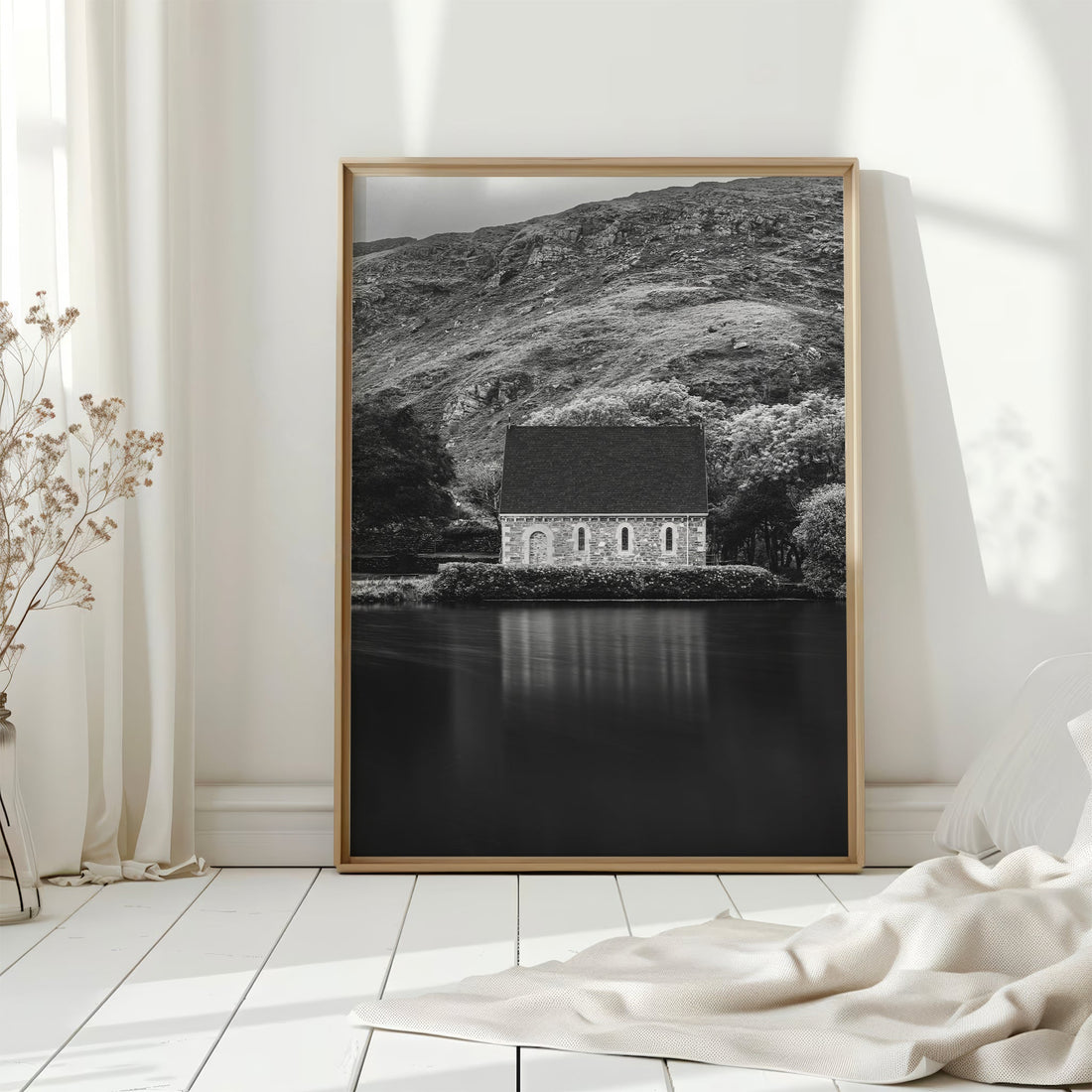 Sunlit framed print of Gougane Barra chapel on white wooden floor