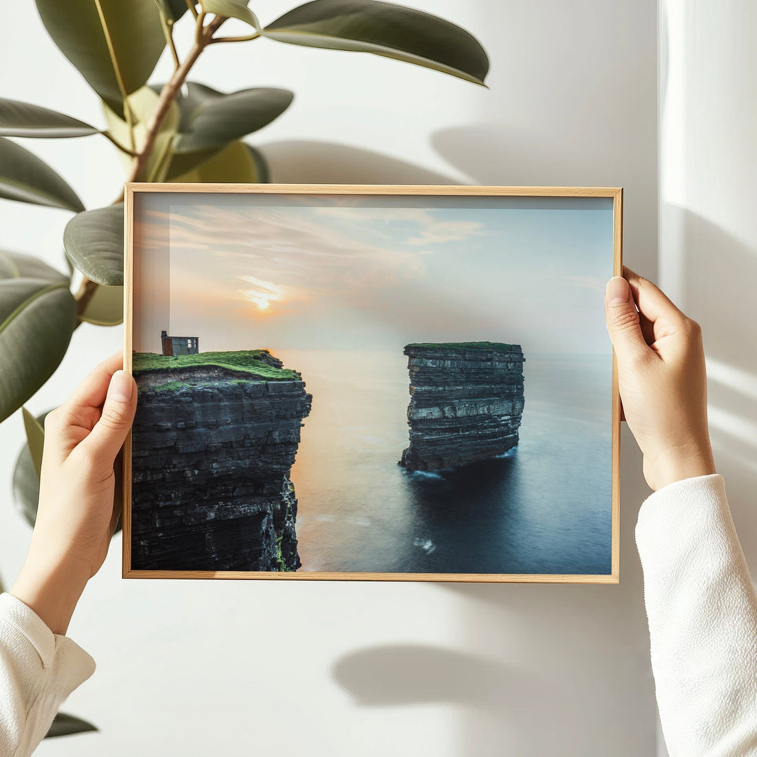 Hands holding a Downpatrick Head photo print with sea stack and sunset colours