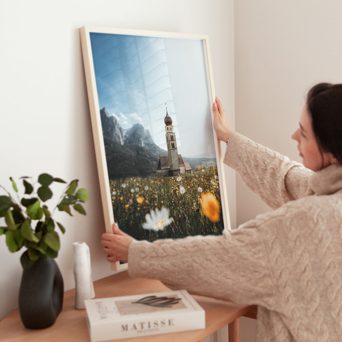 Woman decorating with a framed print of San Valentino church and wildflower meadow