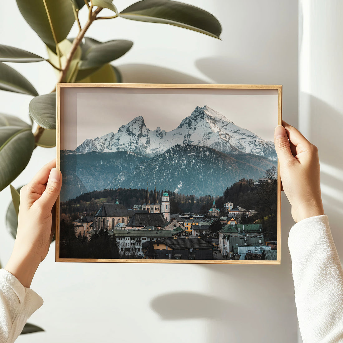 Woman holding framed print of Berchtesgaden with mountains in background