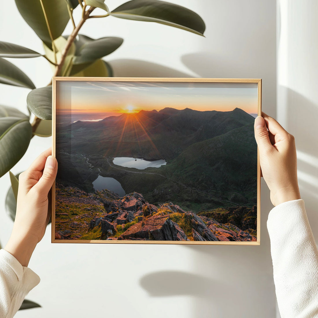 Woman holding framed Carrauntoohil sunrise landscape print.