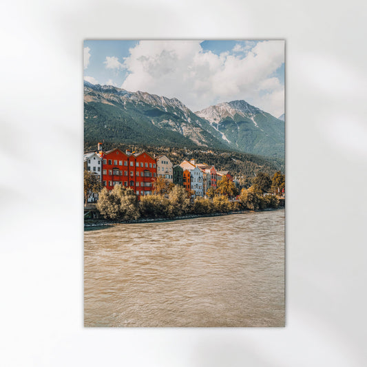 Woman hanging Innsbruck city wall print with bright coloured houses and mountains.